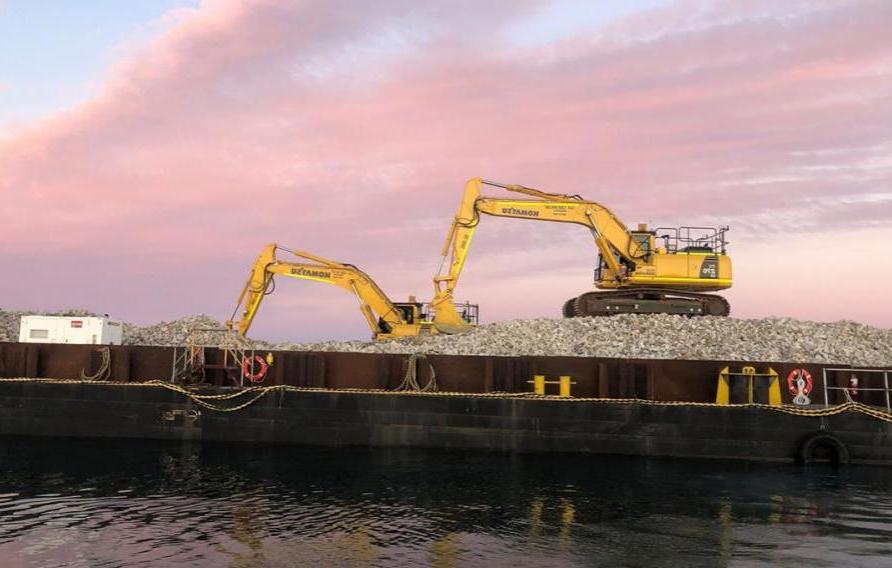 Two excavators at work on Windara Reef construction with pink sky at sunset behind them